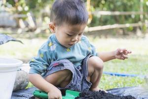 Little child shovels soil into pots to prepare plants for planting. Toddler boy digging soil for planting to Mother's little helper. Gardening. Hobbies at home horticulture. Leisure activities concept photo