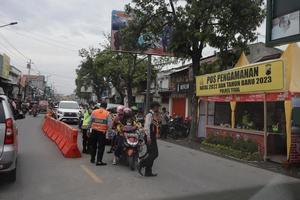 Tegal,December 2022. A group of people walked down a busy city street, using various modes of transportation along the trees and plants. photo