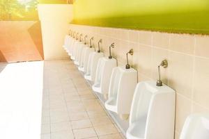 Row of urinal toilet blocks for man on tiled wall photo