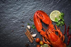 Red lobster seafood with lemon herbs and spices on dark backgroud top view photo