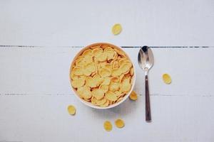 copos de maíz desayuno en cuenco y cuchara en de madera antecedentes - cereal sano comida foto