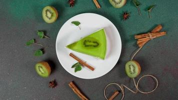 Slice Cheesecake with Kiwi. Decorated with slice of kiwi, cinnamon sticks, badyan, mint leaves. Top view video