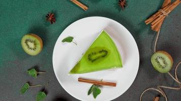 Slice Cheesecake with Kiwi. Decorated with slice of kiwi, cinnamon sticks, badyan, mint leaves. Top view video