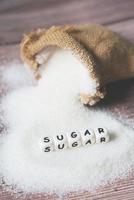 azúcar en sacos y fondo de madera, azúcar blanco para alimentos y dulces dulces de postre montón de azúcar dulce granulado cristalino foto
