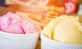 ice cream cup on wooden tray Yellow vanilla and strawberry ice cream scoop on the table background top view photo