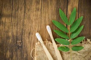 bamboo toothbrush and green leaf on rustic background - Zero waste Bathroom use less plastic concept photo