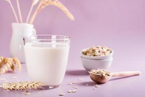 Homemade oat milk in a glass and oatmeal on the table. Alternative to lactose photo