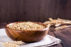 Oat seeds in a wooden bowl and ears on the table. Organic harvest. photo