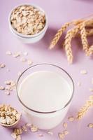 A glass of fresh oat milk and oatmeal. Vegan dairy-free organic drink. Vertical view photo