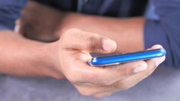 Feche a mão do jovem usando um telefone inteligente video