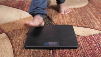 Young man's feet on weight scale close up video