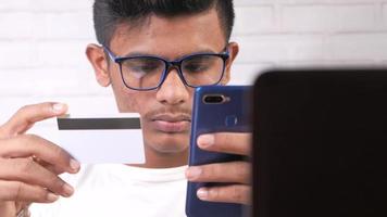 joven asiático hombre participación crédito tarjeta y utilizando inteligente teléfono compras en línea video