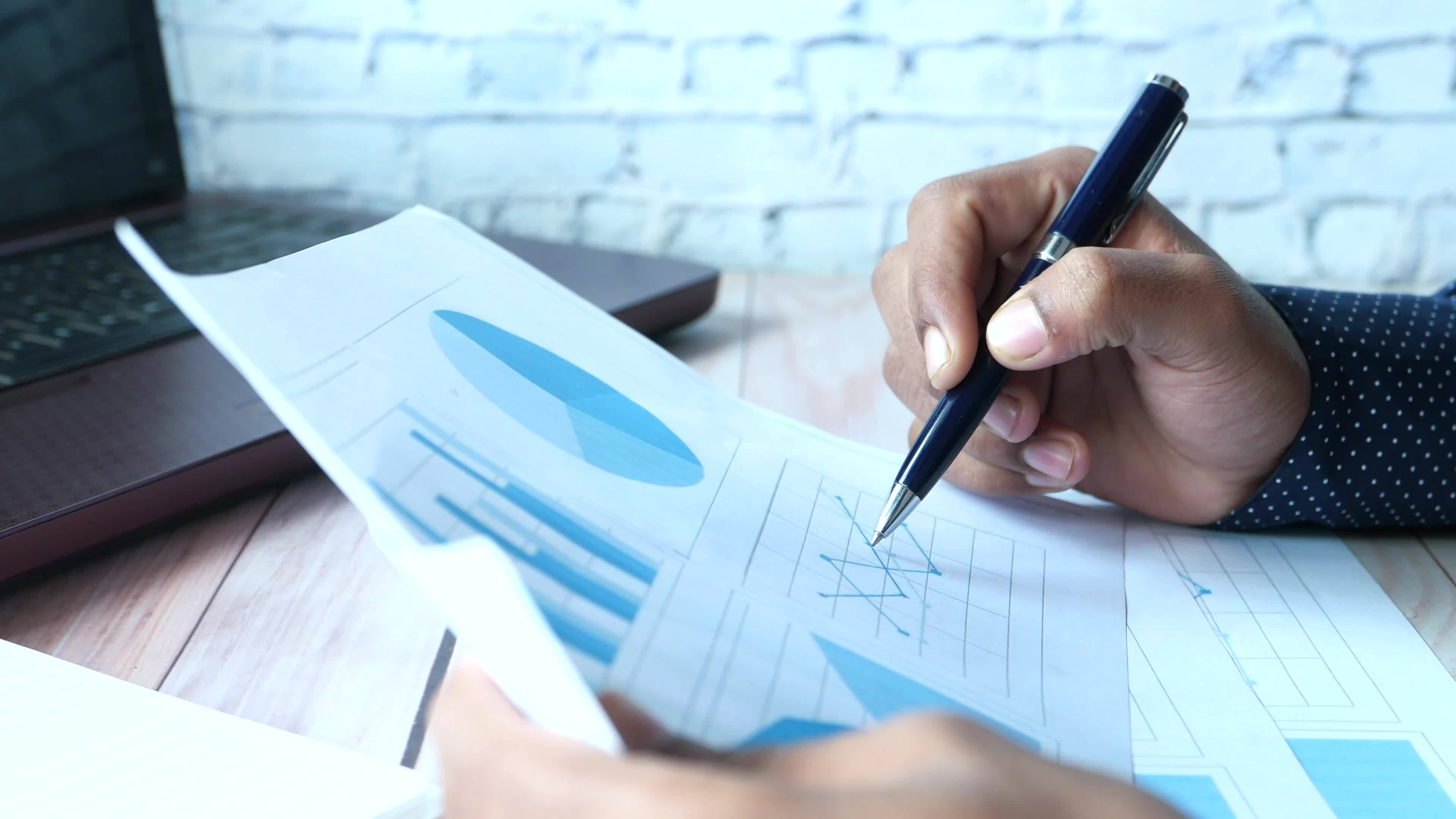 Businessman hand with pen analyzing financial chart on paper 21721496