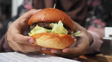 hand holding beef burger on table close up video