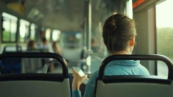 Woman in tram using smartphone chatting and texting with friends, back view video