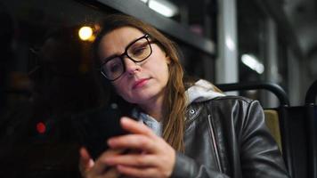 Public transport at night. Woman in glasses in tram using smartphone video