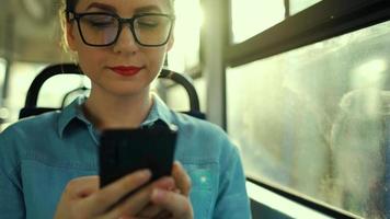Public transport. Woman in glasses in tram using smartphone. Slow motion