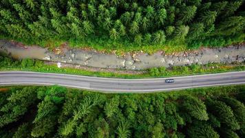 Top down view of cars driving along the road among the coniferous forest video