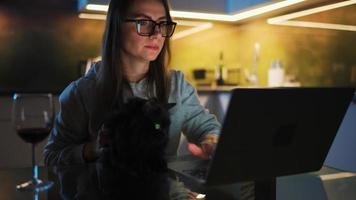 mujer es sentado en el cocina y trabajando en un ordenador portátil a noche video