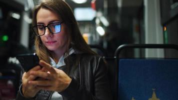 Öffentlichkeit Transport beim Nacht. Frau im Brille im Straßenbahn mit Smartphone video