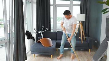 Man cleaning the house and having fun dancing and singing with a broom. video
