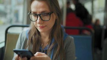 vrouw in tram gebruik makend van smartphone chatten en sms'en met vrienden. video