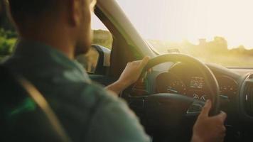 Mann fährt ein Auto entlang das Straße, das Rahmen Sonne scheint im das Windschutzscheibe. video