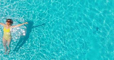 oben Nieder Aussicht von ein Frau im Gelb Badeanzug Lügen auf ihr zurück im das Schwimmbad. video