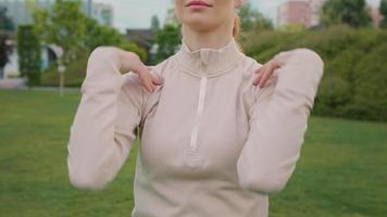 vrouw aan het doen warm omhoog oefening roterend schouders in de park, sport net zo routine. video