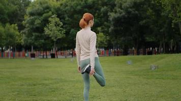 Back view of young woman do legs stretch after outdoor exercise. video