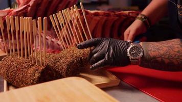 Chef hands taking a seasoned beef roulade with spiced and skewers from a tray. video