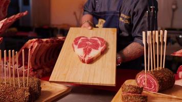 Zoom in shot of cooks hands showing wooden board with raw beef ribeye steak meat. video
