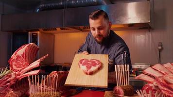 Butcher displaying heart shape raw fresh meat beef ribeye steak. video