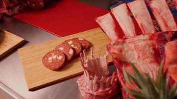 Scheiben von hausgemacht Würstchen auf ein hölzern süß Tafel entlang mit Schweinefleisch und Lamm Rippchen. video