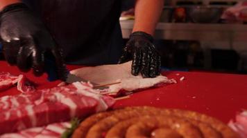 Butcher with black gloves cutting raw lamb loin chopsin the kitchen. video