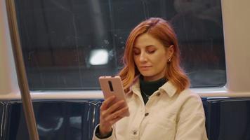 Portrait of woman on train using smartphone scrolling.