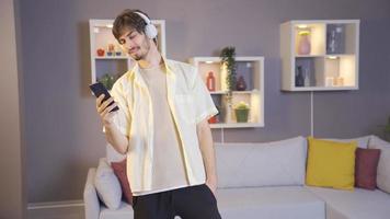 Happy young man listening to music with headphones at home. Happy and cheerful young man listening to music on the phone with headphones at home. video