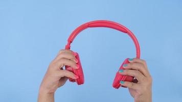 Female hands holding headphones on pastel blue background in studio. Body language concept. With place for text or image, promotional content. video