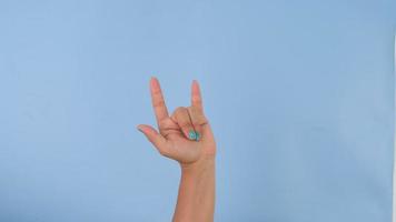 kvinna hand som visar jag kärlek du tecken isolerat på pastell blå bakgrund i studio. packa av gester rörelser och kropp språk. kärlek hand tecken video