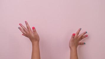 Nahansicht von angehoben Kind Hand zeigen Nagel Polieren und winken auf Pastell- Rosa Hintergrund im Studio. Pack von Gesten Bewegungen und Körper Sprache. video