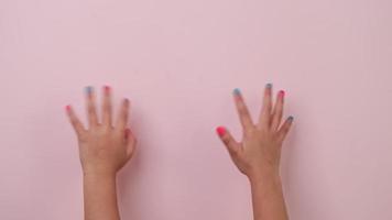 Close-up of raised child hand showing nail polish and waving on pastel pink background in studio. Pack of Gestures movements and body language. video