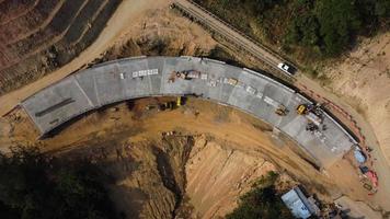 aereo Visualizza di sviluppo di nuovo strada costruzione o cavalcavia sotto costruzione. superiore Visualizza a partire dal un' fuco sopra strada costruzione lavoratori tra il montagne. video