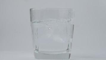 Nahansicht von fallen Eis Würfel im rein Trinken Wasser im Glas isoliert auf Weiß Hintergrund. video