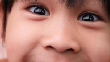 Close-up of beautiful black eyes of a cute little asian girl, wide open black eyes looking at camera. video