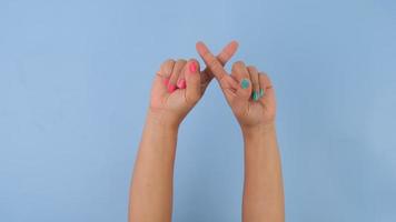 hembra manos cruzado dedos demostración detener gesto en pastel azul antecedentes en estudio. paquete de gestos movimientos y cuerpo idioma. video