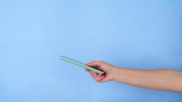 vrouw hand- geven mobiel telefoon Aan pastel blauw achtergrond in studio. video