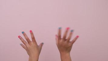 Nahansicht von angehoben Kind Hand zeigen Nagel Polieren und winken auf Pastell- Rosa Hintergrund im Studio. Pack von Gesten Bewegungen und Körper Sprache. video