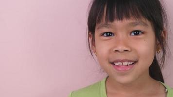 Portrait of happy smiling girl isolated on pink background in studio. Funny little girl smiling looking at camera at home. Concept of happy childhood video