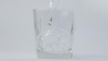 Gießen frisch rein Trinken Wasser in Glas isoliert auf Weiß Hintergrund. Nahansicht von Hand Gießen Wasser von Flasche in Glas. video