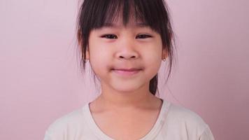 Portrait of happy smiling girl isolated on pink background in studio. Funny little girl smiling looking at camera at home. Concept of happy childhood video